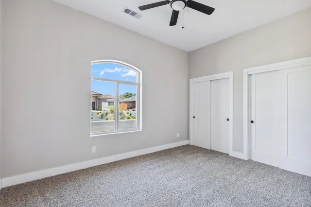 an empty room with windows and fan