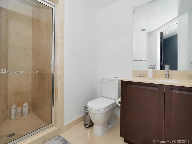 a bathroom with a sink a toilet a mirror and shower
