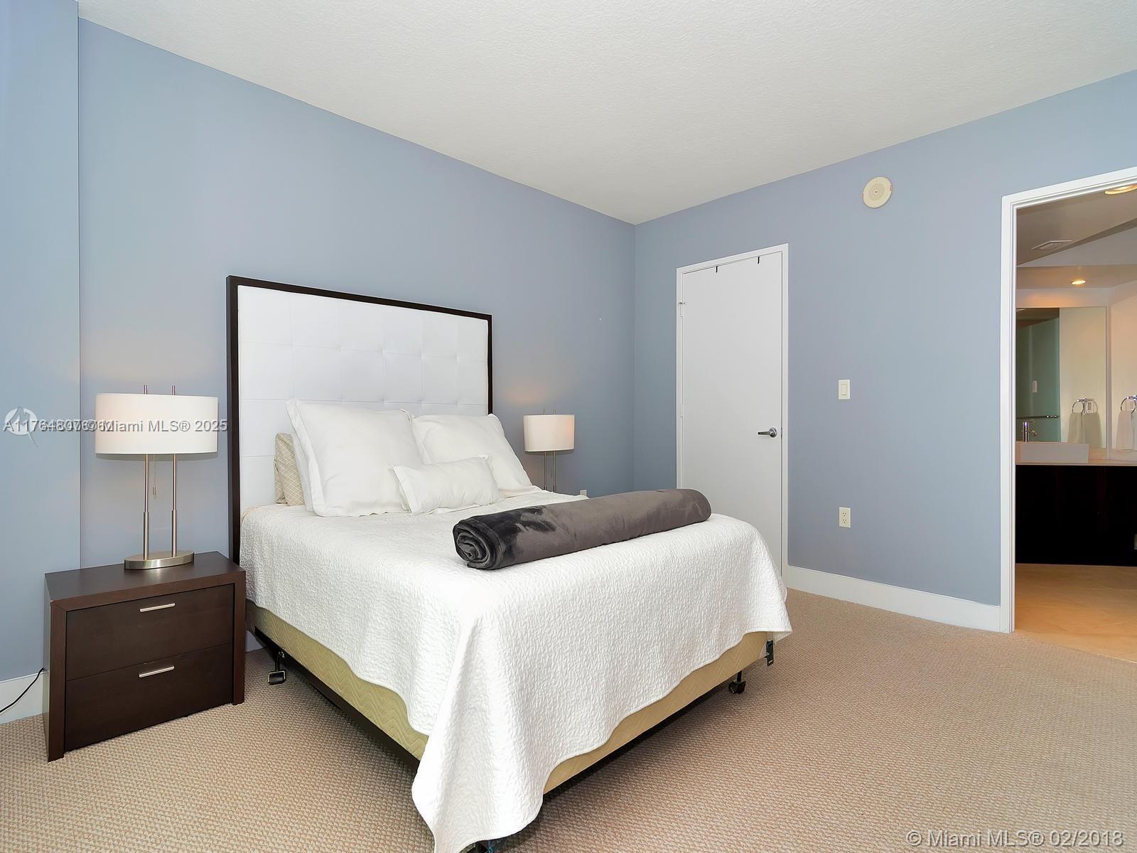 250 Sunny Isles Boulevard, Unit 31403 Sunny Isles Beach, FL 33160 - Photo 10 of 24 a bedroom with a bed and a lamp