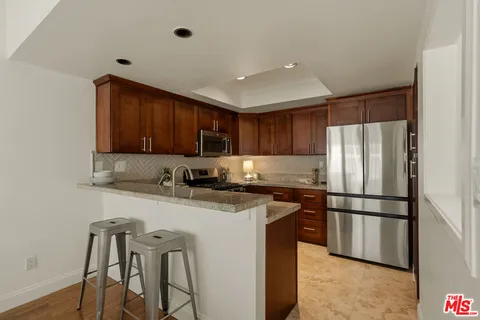 a kitchen with stainless steel appliances granite countertop a refrigerator a stove a sink dishwasher and a microwave with wooden floor