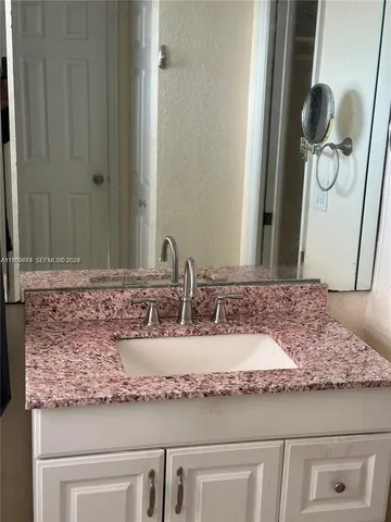 a bathroom with a granite countertop sink and a mirror
