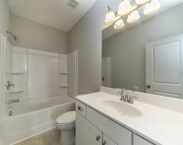 a bathroom with a sink a toilet a mirror a bathtub and shower