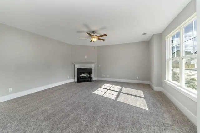 an empty room with windows and ceiling fan