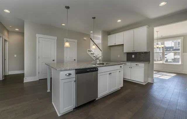 a kitchen with granite countertop a sink cabinets and wooden floor