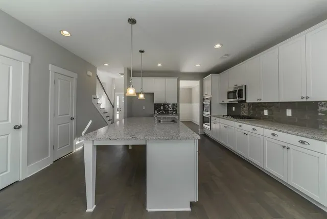 a large kitchen with stainless steel appliances granite countertop a sink a stove and a refrigerator