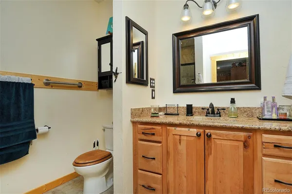 a bathroom with a granite countertop toilet sink and mirror