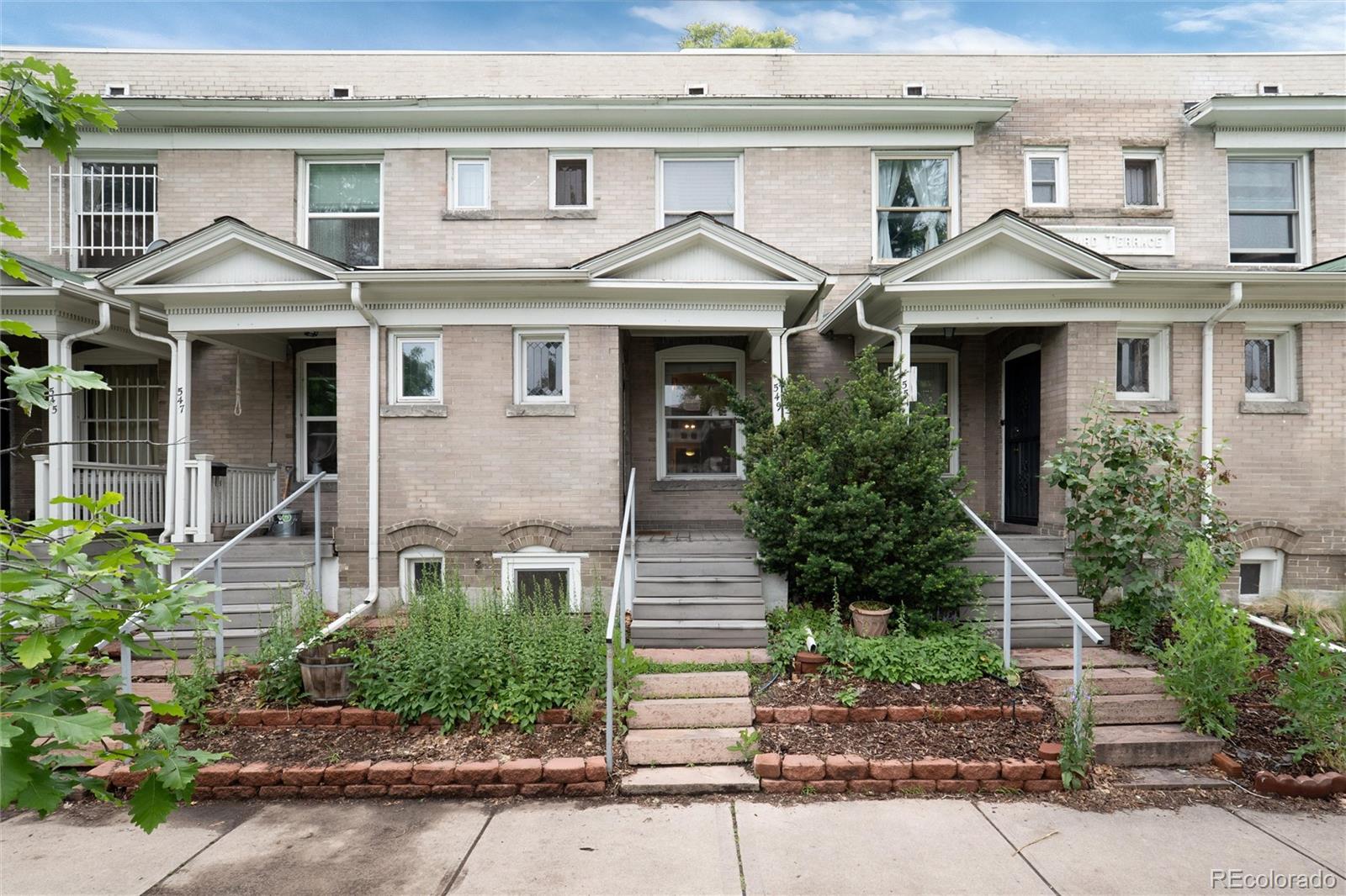 a front view of a house with a yard and potted plants