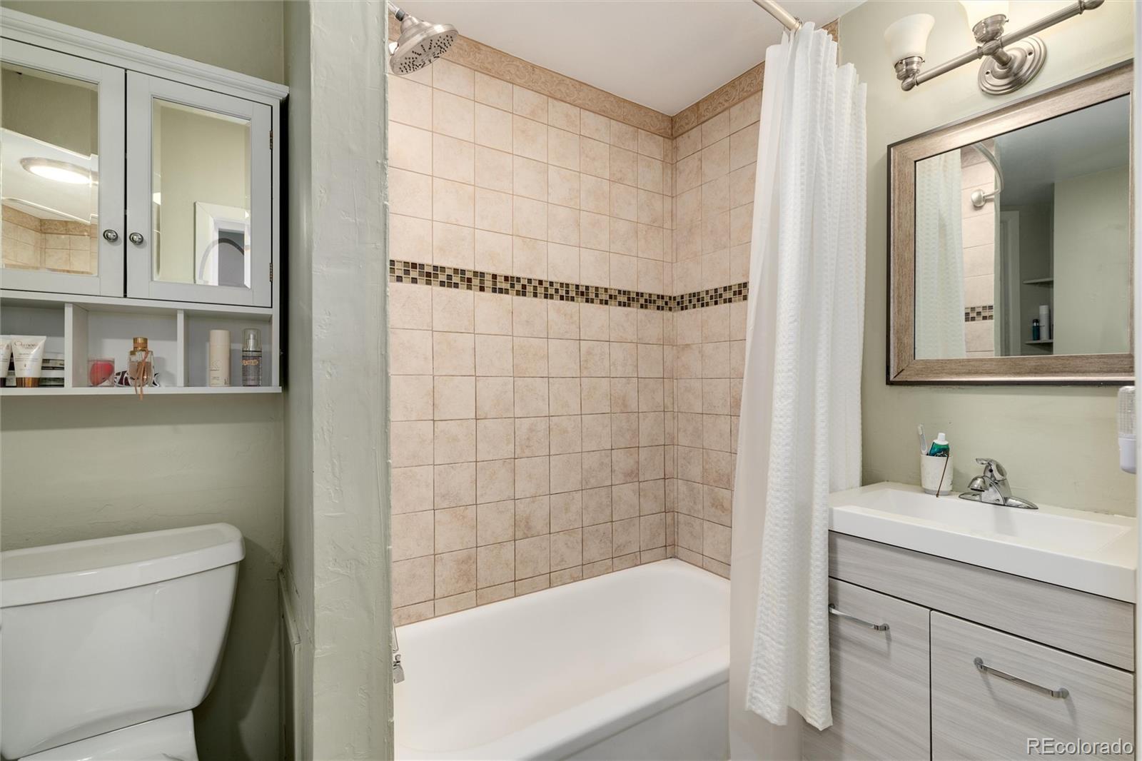 549 Logan Street Denver, CO 80203 - Photo 9 of 14 a bathroom with a granite countertop bathtub shower sink vanity and toilet