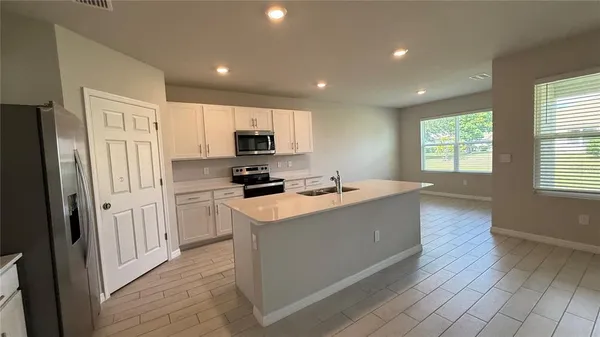 a kitchen with sink a microwave refrigerator and cabinets