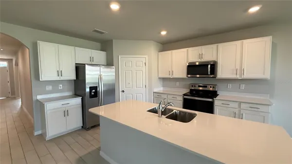 a kitchen with stainless steel appliances kitchen island a white cabinets sink and a refrigerator