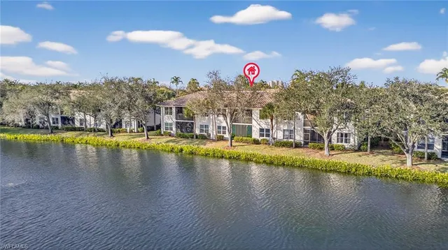a view of a swimming pool that has lawn chairs and a dining table under an umbrella