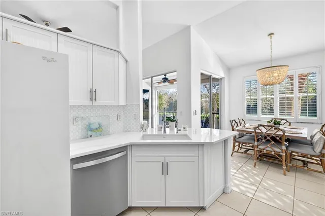 a dining hall with stainless steel appliances granite countertop a sink dishwasher and white cabinets with wooden floor