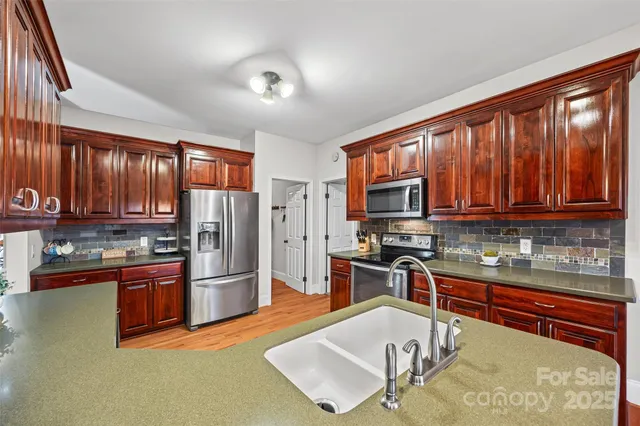 a kitchen with stainless steel appliances granite countertop a refrigerator stove top oven and sink