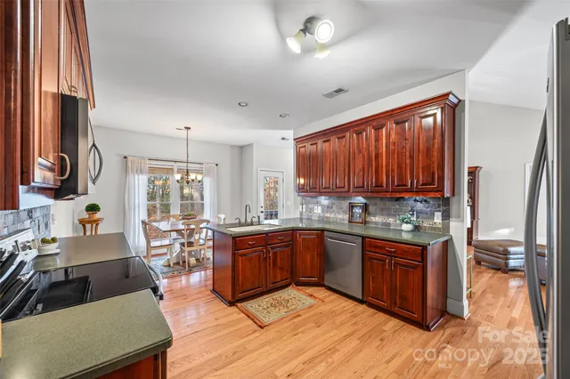 a large kitchen with stainless steel appliances granite countertop sink stove and cabinets