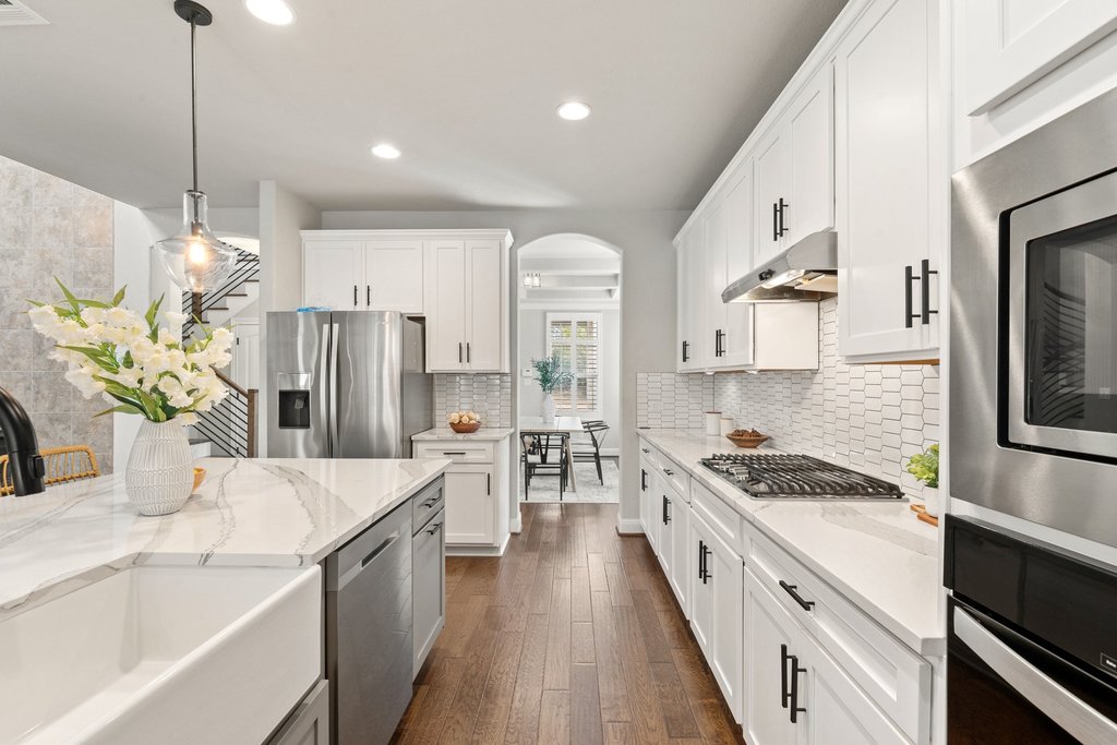 4229 Borho Ranch Street Leander, TX 78641 - Photo 10 of 40 Kitchen featuring stainless steel appliances, white cabinets, dark wood finished floors, and hanging light fixtures