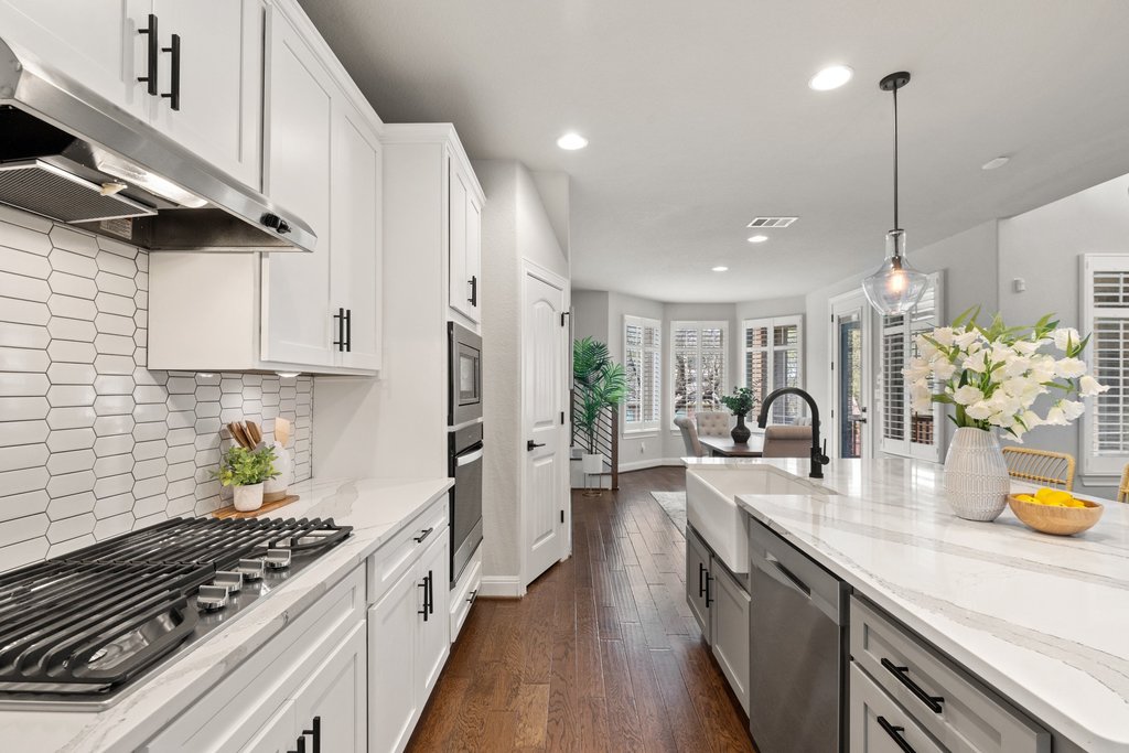 4229 Borho Ranch Street Leander, TX 78641 - Photo 11 of 40 Kitchen with stainless steel appliances, dark wood-style flooring, light stone countertops, pendant lighting, and dual tone cabinetry