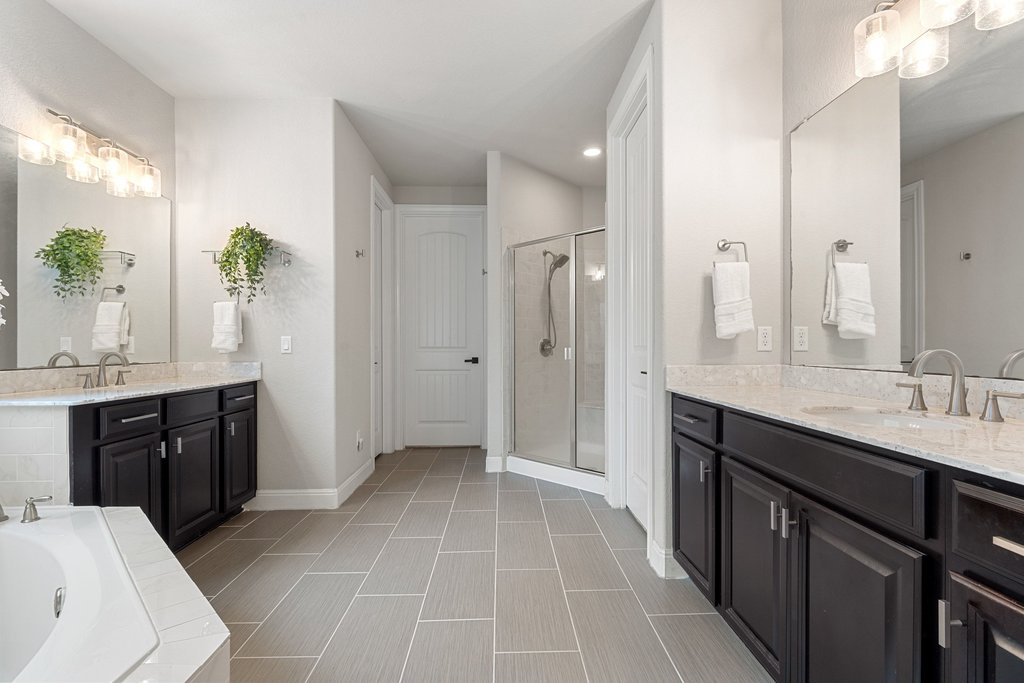 4229 Borho Ranch Street Leander, TX 78641 - Photo 16 of 40 Bathroom featuring two vanities, a garden tub, and a shower stall