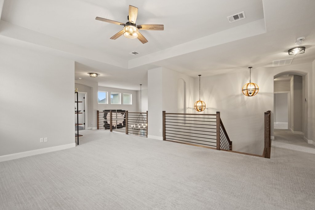 4229 Borho Ranch Street Leander, TX 78641 - Photo 23 of 40 Spare room featuring a tray ceiling, carpet flooring, and a ceiling fan