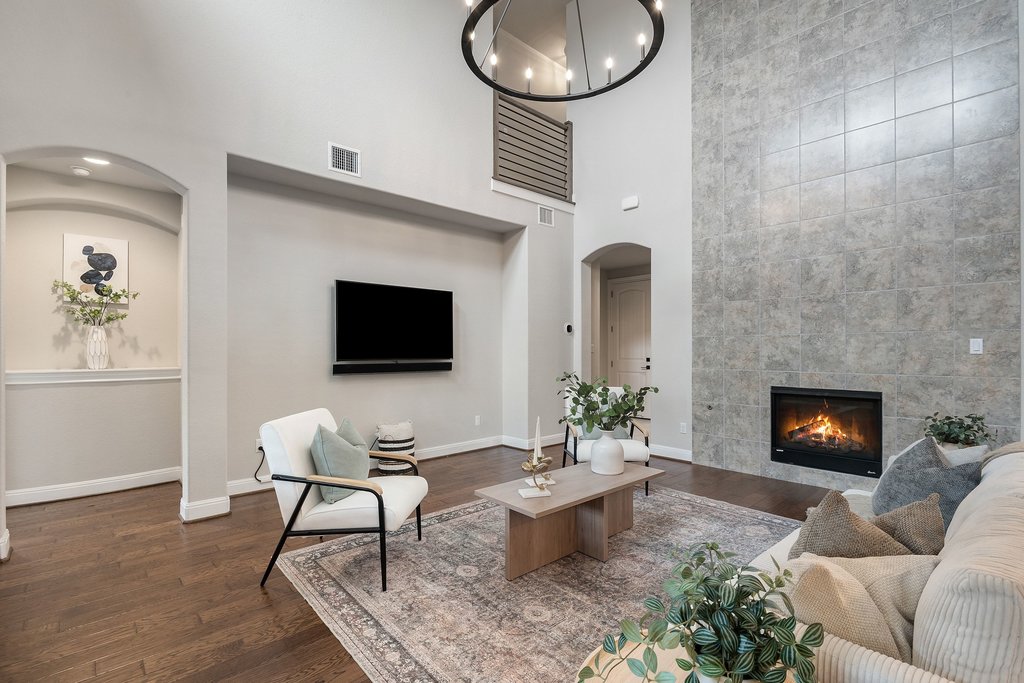 4229 Borho Ranch Street Leander, TX 78641 - Photo 5 of 40 Living room with arched walkways, dark wood finished floors, a high ceiling, a fireplace, and suspended lighting