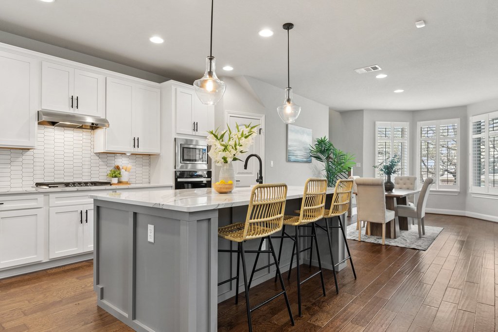 4229 Borho Ranch Street Leander, TX 78641 - Photo 8 of 40 Dual tone kitchen featuring a center island with sink, decorative backsplash, dark wood-type flooring, a kitchen breakfast bar, and light stone counters