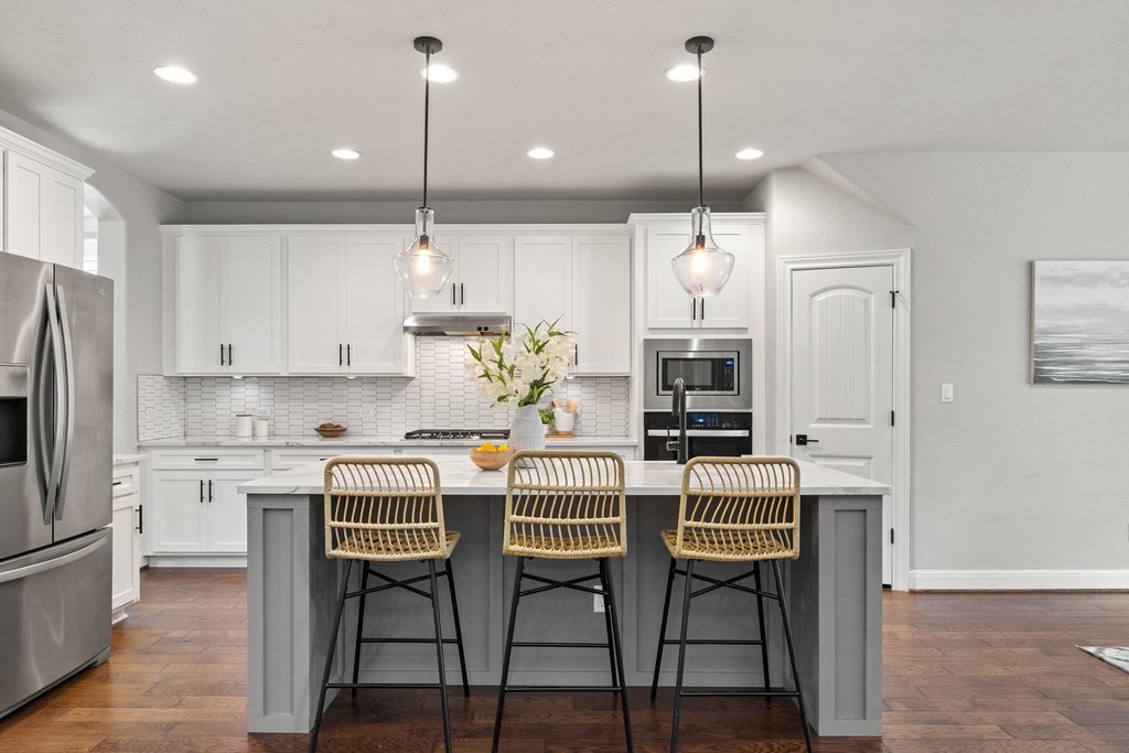 4229 Borho Ranch Street Leander, TX 78641 - Photo 9 of 40 Kitchen with stainless steel appliances, decorative light fixtures, a center island with sink, a breakfast bar, and dual tone cabinets