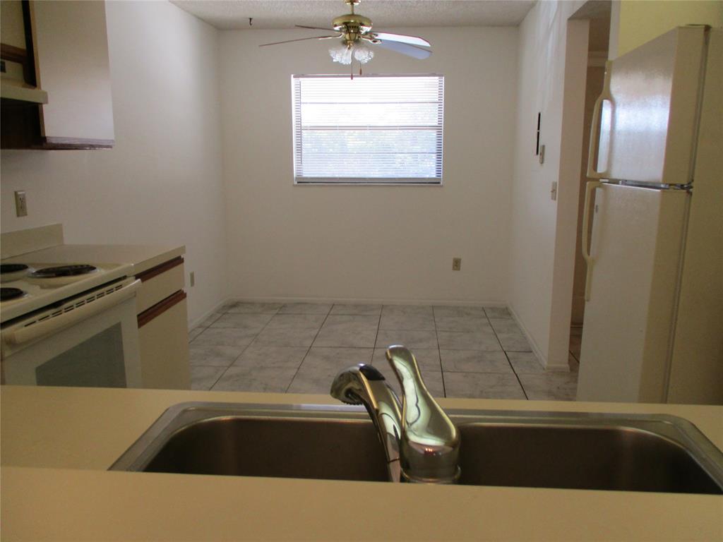 23442 Southwest 57th Avenue, Unit 406 Boca Raton, FL 33428 - Photo 7 of 25 a view of a kitchen counter space a sink wooden floor and a stove top oven