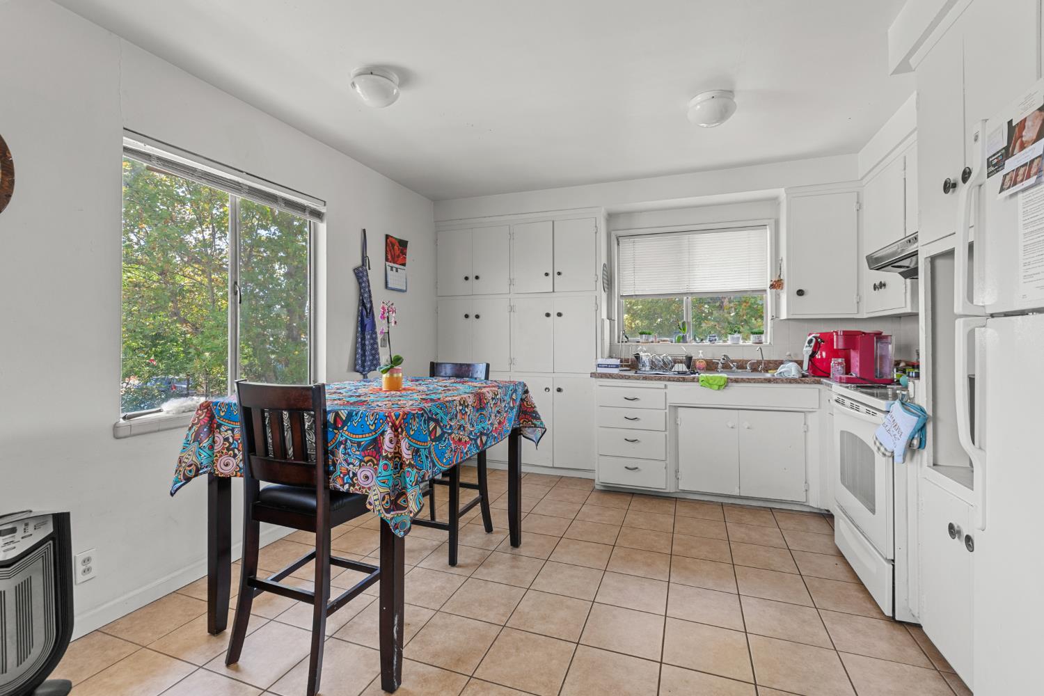 2123 15th Avenue Sacramento, CA 95822 - Photo 17 of 35 a kitchen that has white cabinets a stove and a dining table with chairs