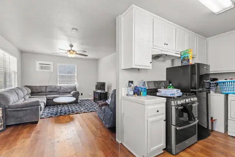 a open kitchen with stainless steel appliances granite countertop a stove top oven a refrigerator a sink and dishwasher with white cabinets