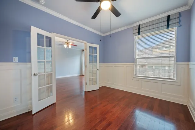 a view of empty room with wooden floor and fan