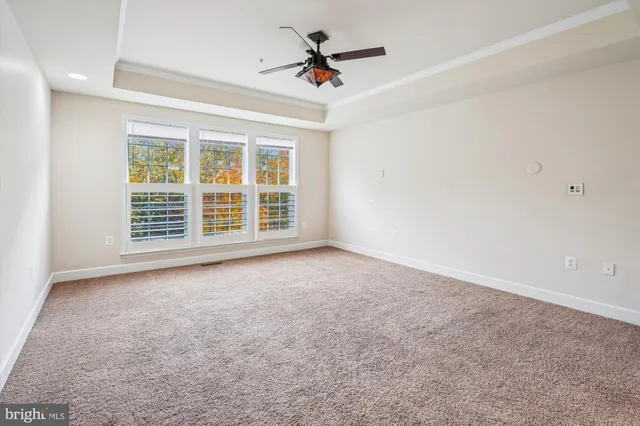an empty room with windows and ceiling fan