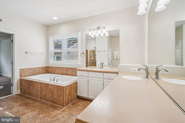 a bathroom with a tub a double vanity sink a window a mirror and