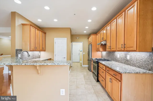 a large kitchen with granite countertop kitchen island a sink a stove and a refrigerator