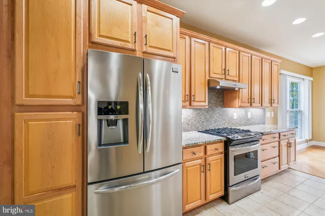 a kitchen with stainless steel appliances granite countertop a refrigerator and a stove top oven