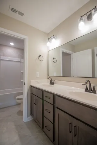 a bathroom with a double vanity sink mirror and toilet