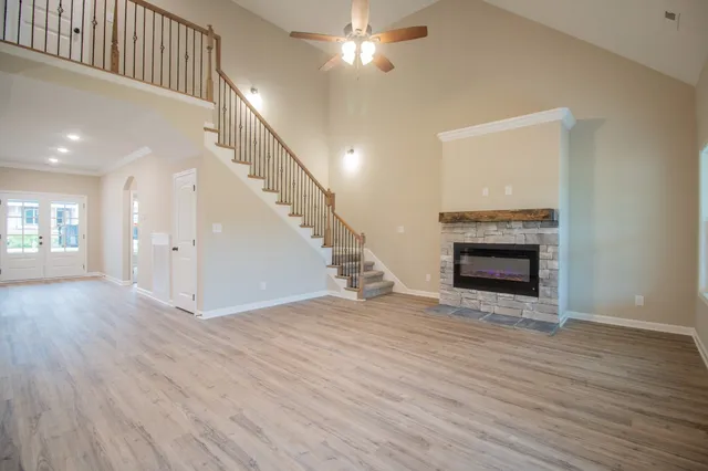 a view of an empty room with wooden floor fireplace and a window