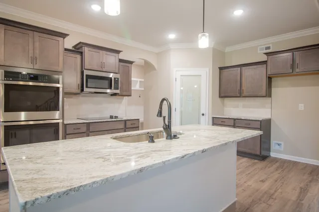 a kitchen with stainless steel appliances granite countertop a sink microwave and refrigerator