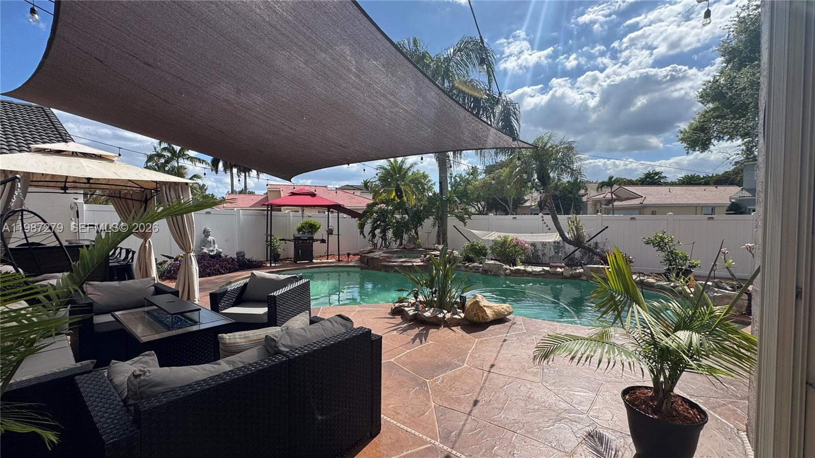 4220 Southwest 153rd Avenue Miramar, FL 33027 - Photo 34 of 34 a view of a patio with couches table and chairs under an umbrella