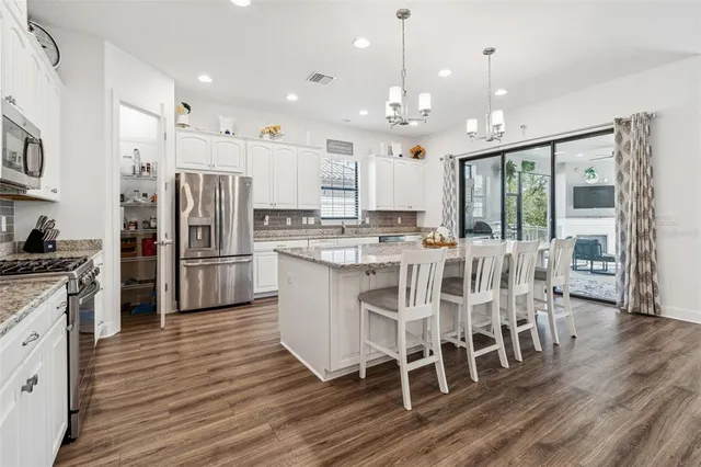 a large kitchen with granite countertop a large counter top a sink stainless steel appliances and cabinets