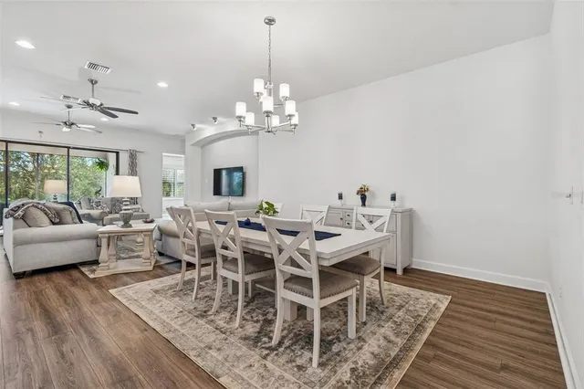 a kitchen with stainless steel appliances kitchen island granite countertop a refrigerator a stove a oven and white cabinets with wooden floors