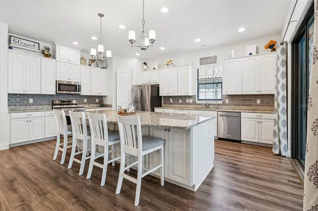 a large kitchen with granite countertop a large counter top space a sink stainless steel appliances and cabinets