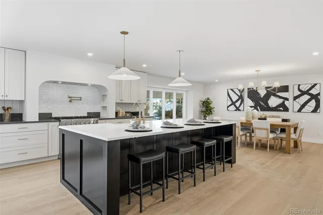 a kitchen with stainless steel appliances granite countertop a sink a stove and a dining table