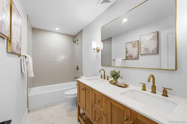 a bathroom with a granite countertop sink a toilet and shower