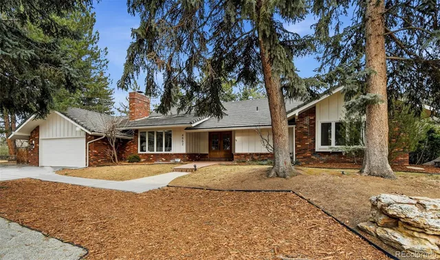 a front view of a house with a yard covered with trees