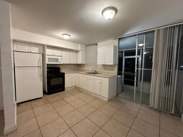 a kitchen with a refrigerator sink and cabinets