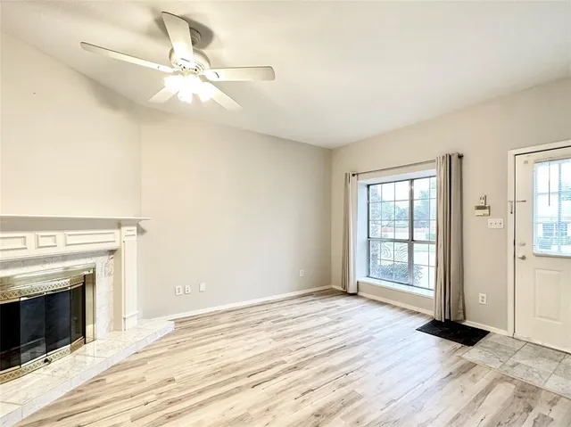 an empty room with wooden floor fan and windows
