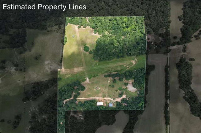 an aerial view of a residential houses with outdoor space and trees