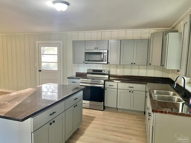 a kitchen with granite countertop a sink stove and cabinets