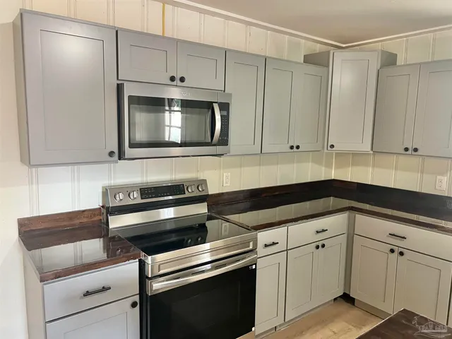 a kitchen with granite countertop white cabinets and stainless steel appliances