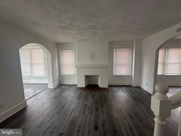 an empty room with wooden floor fireplace and windows
