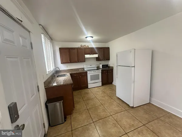 a kitchen with granite countertop a refrigerator and a stove top oven